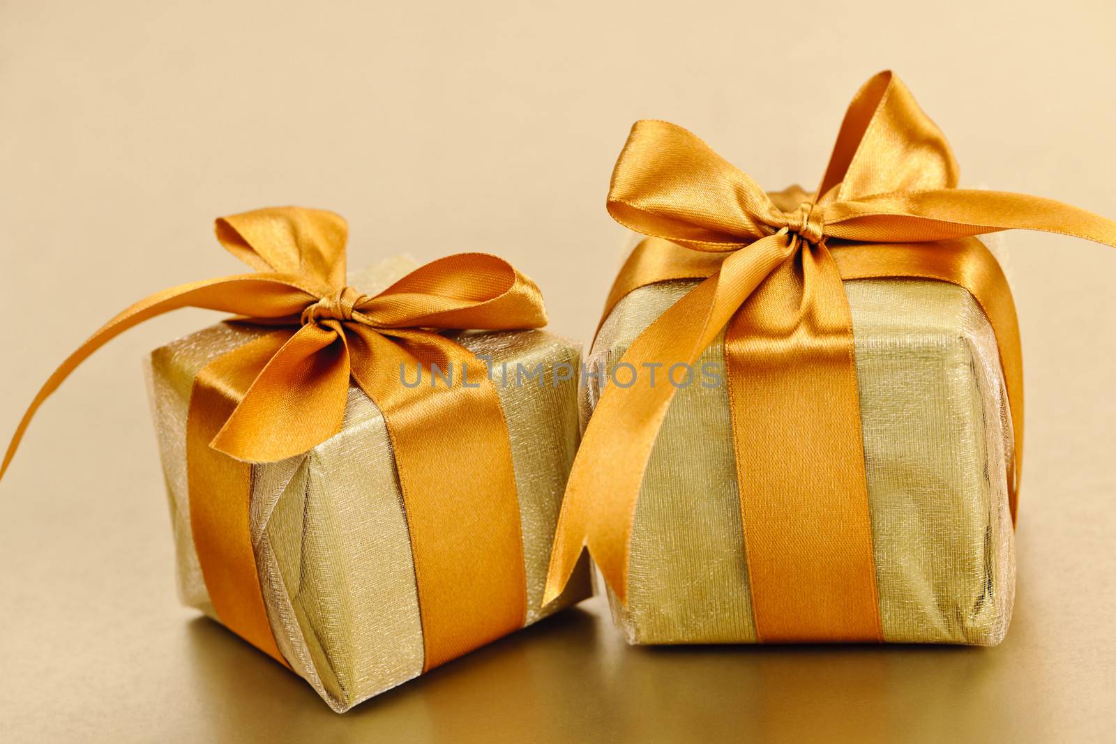 Two gift boxes in gold wrapping paper with ribbon and bow