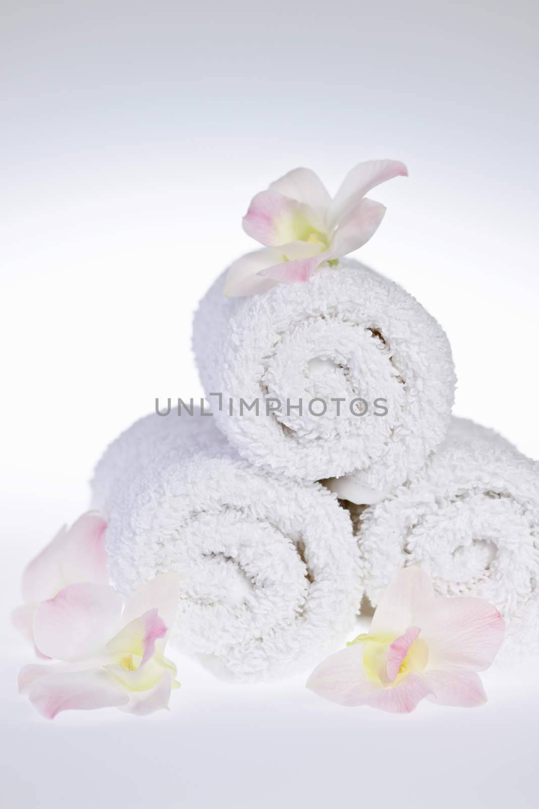 White rolled up spa towels with orchids flowers