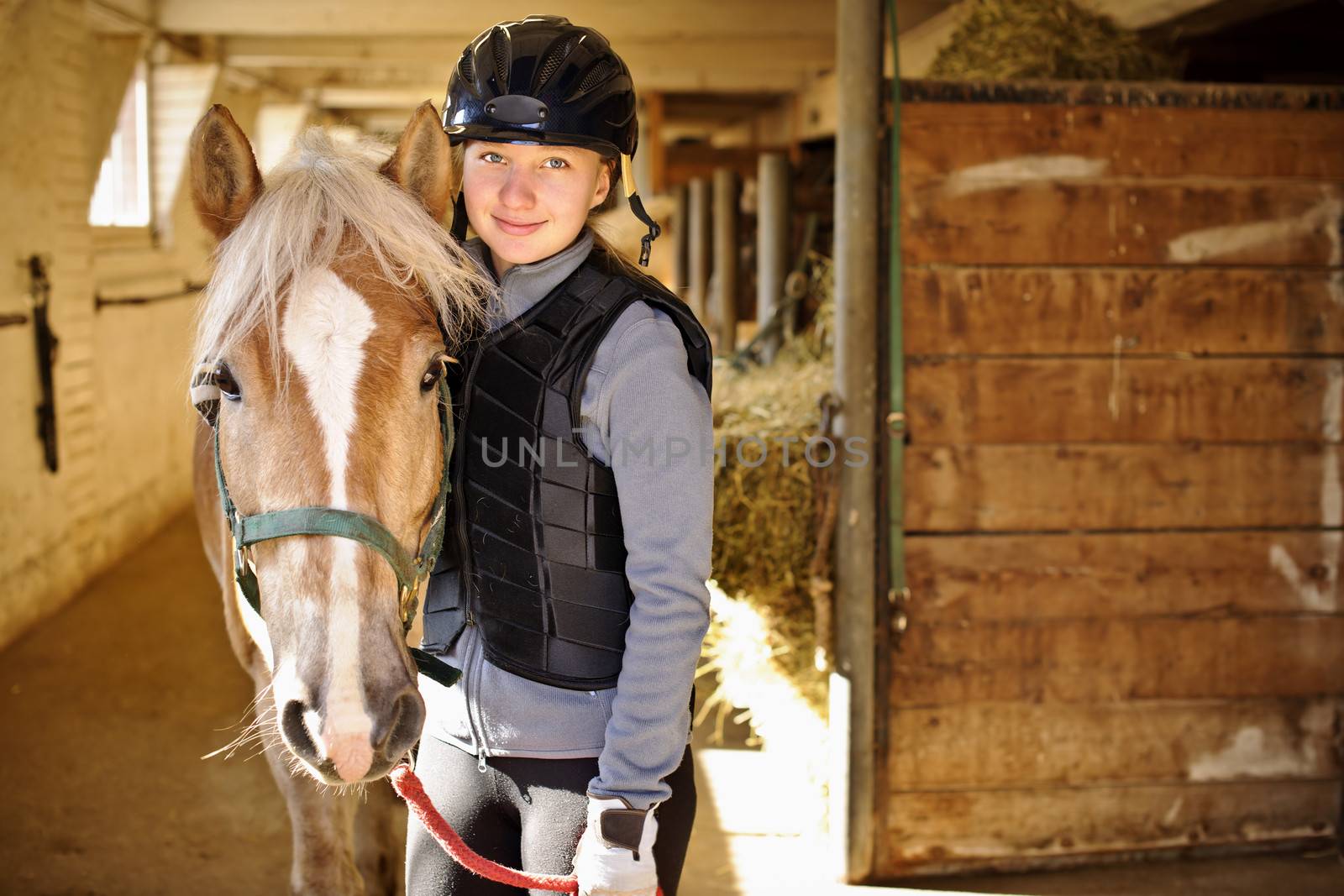 Portrait of teenage girl with horse in stable