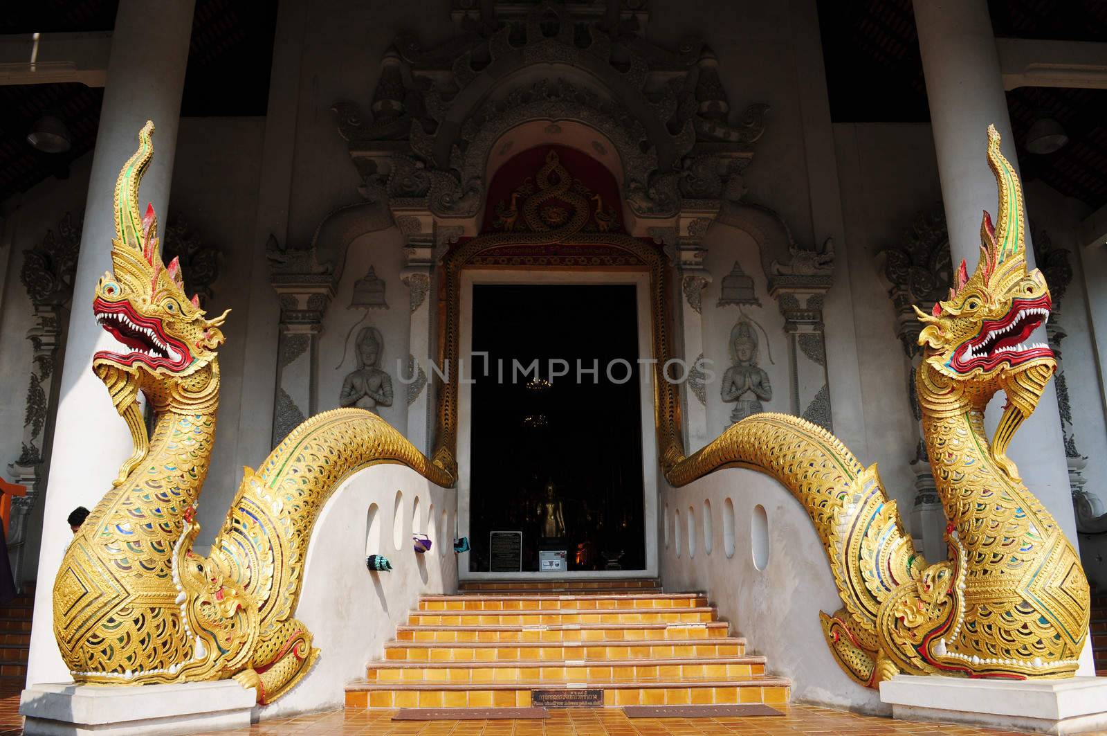 Gate of an ancient wat in Thailand,with two golden dragons 