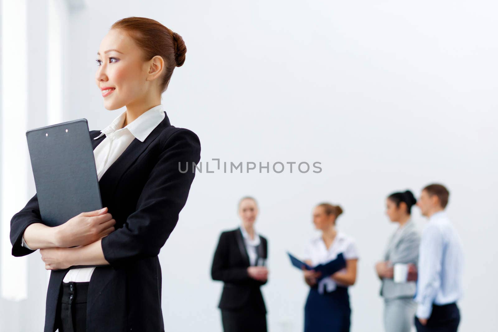 Asian young business woman holding folder with colleagues at background