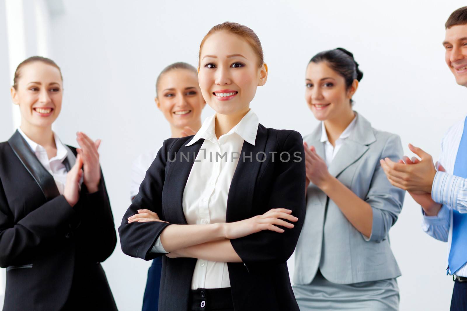 Young asian businesswoman smiling with colleagues applauding joyfully at background