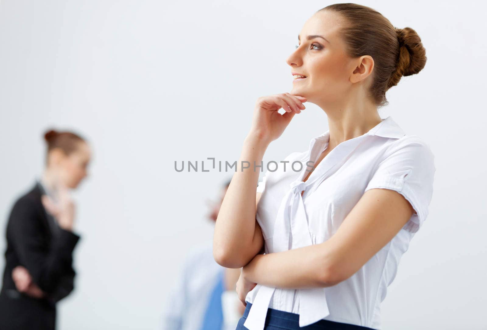 Attractive businesswoman looking thoughtfully with colleagues at background
