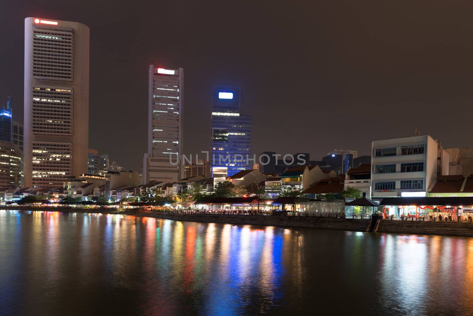 Singapore quay at night with tall skyscrapers in the central business district and and small restaurants on Boat Quay 