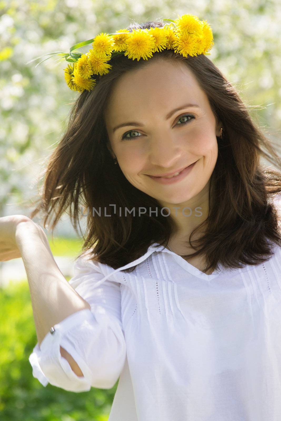 Sensual lovely woman with dandelion wreath in spring garden
