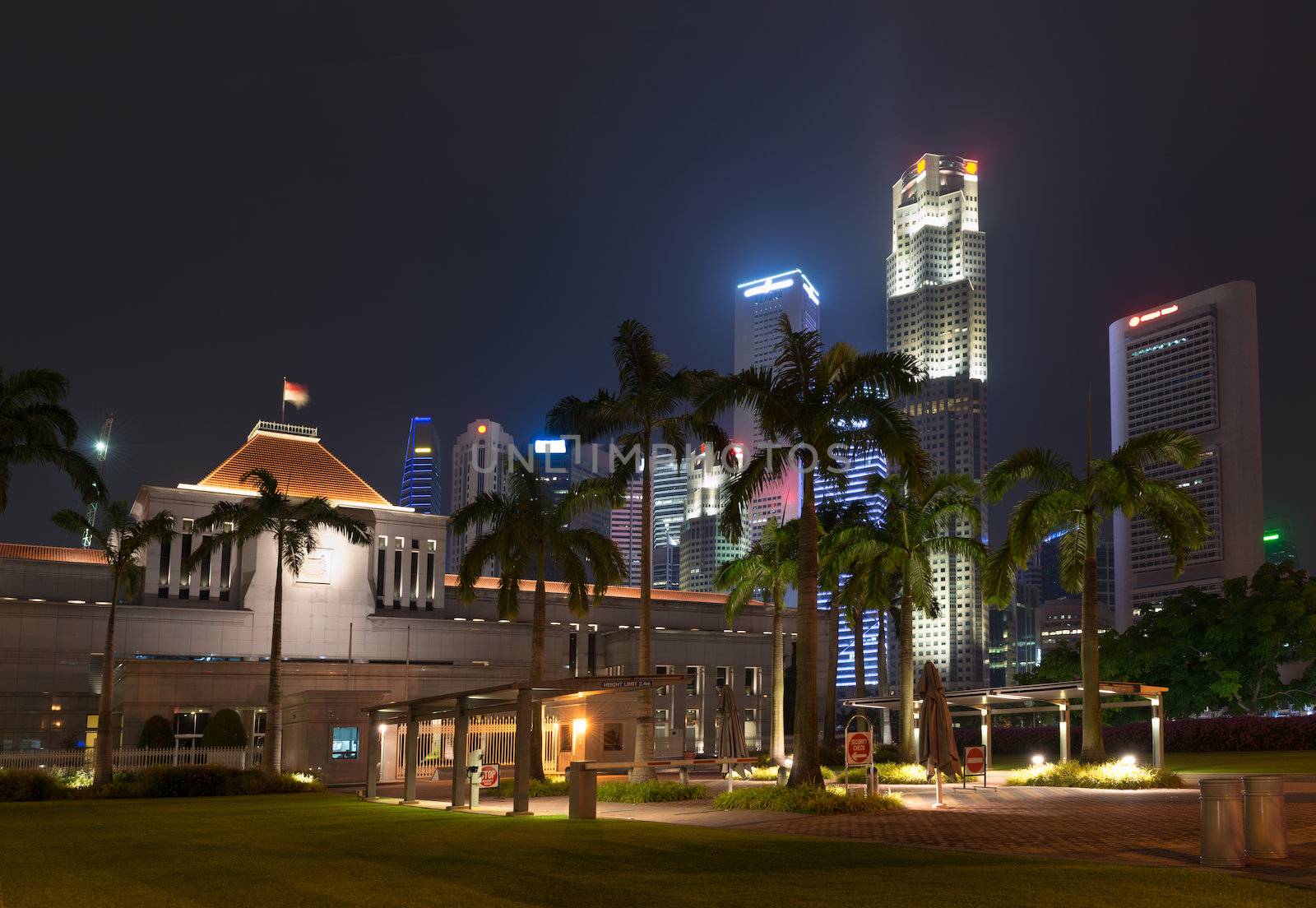 Singapore parliament building illuminated at night with skyscraper on background