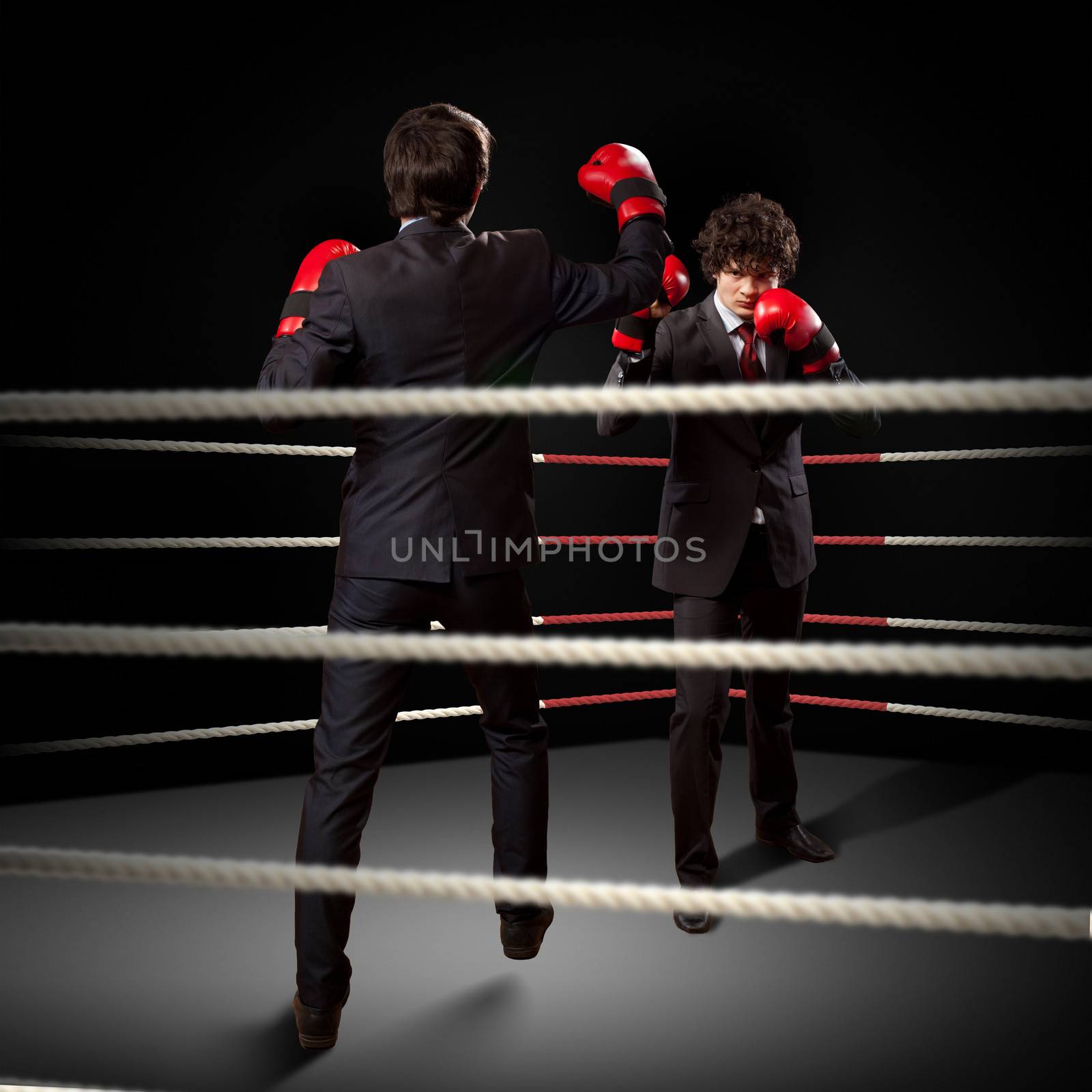 Two young businessman boxing againts dark background . conceptual collage