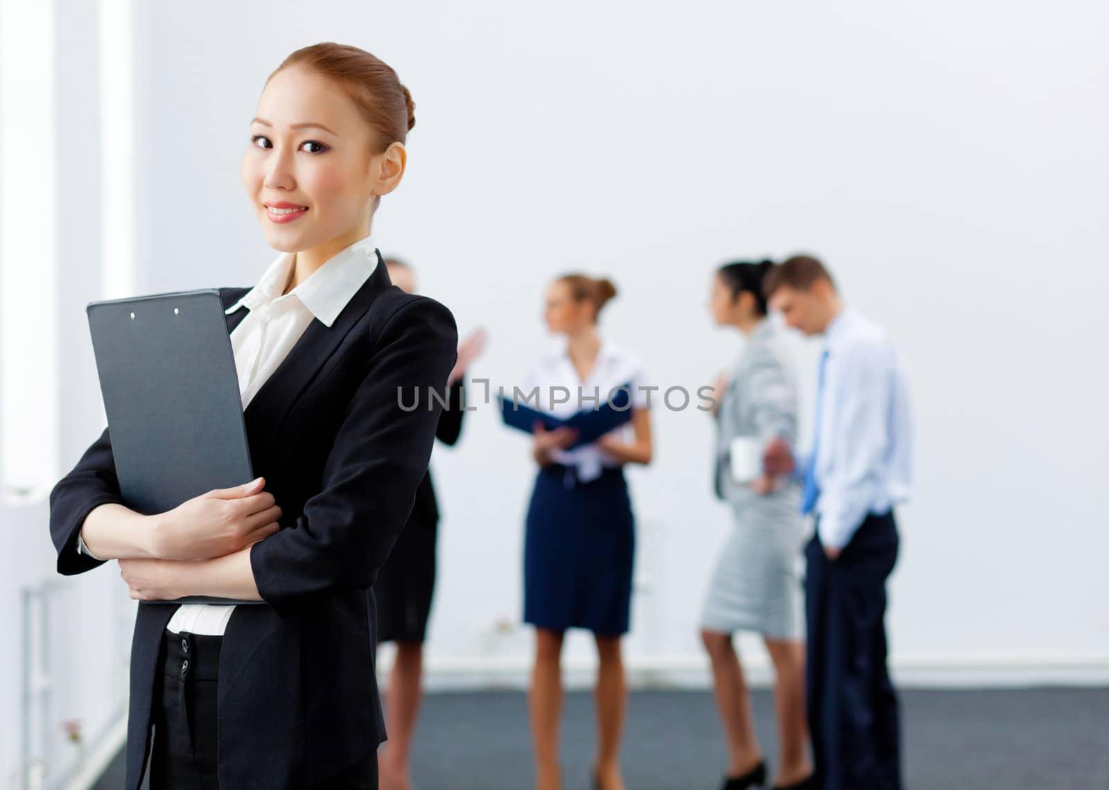 Asian young business woman holding folder with colleagues at background