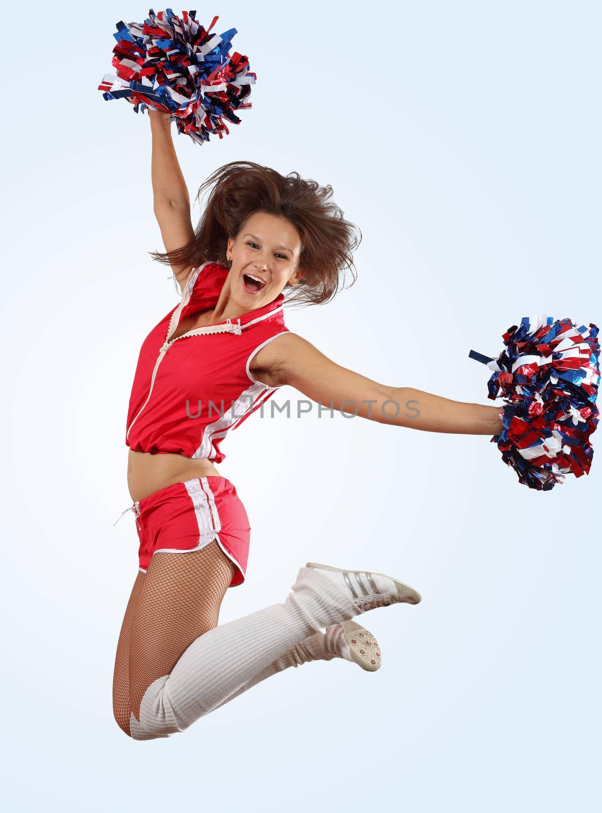 Uniformed cheerleader jumps high in the air isolated on white.