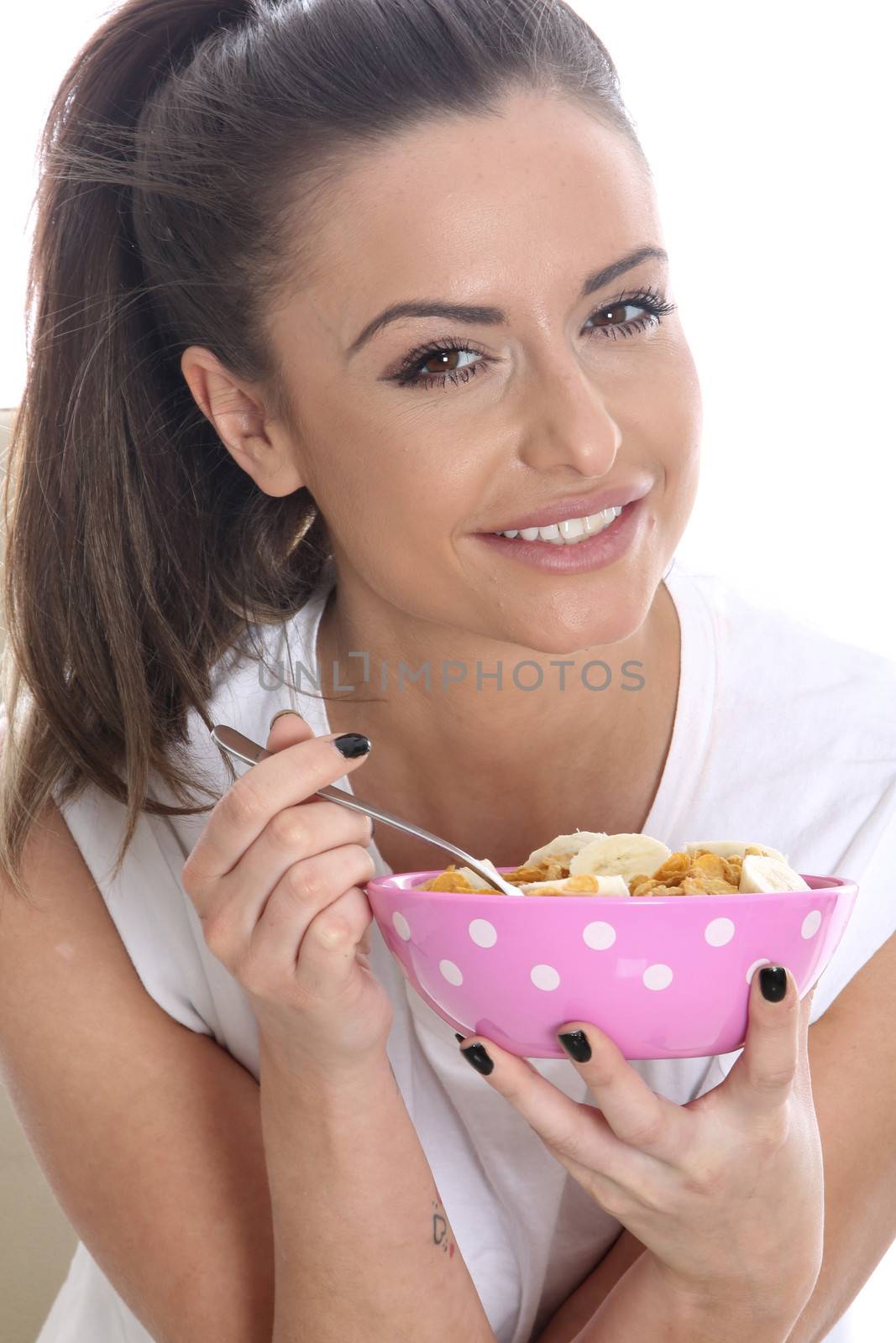 Model Released. Young Woman Eating Breakfast Cereal with Fresh Fruit