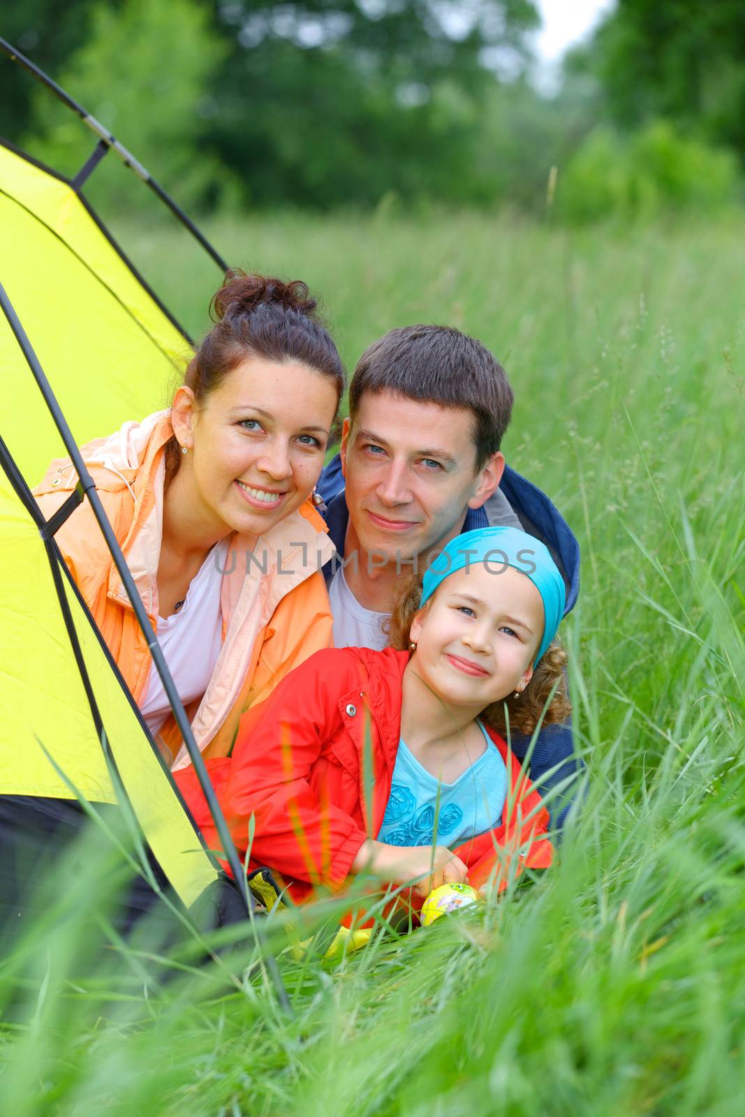 Summer vacation. Family of three in tent in camping on the nature. Vertical view