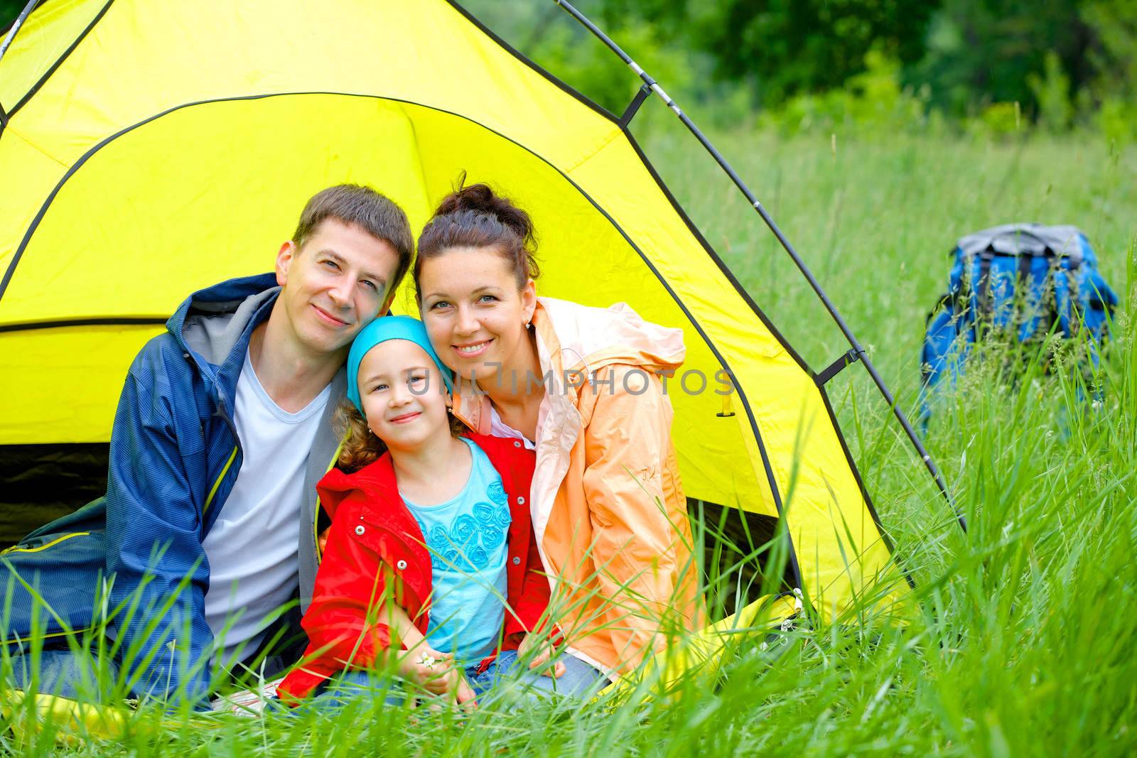 Summer vacation. Family of three in tent in camping on the nature.