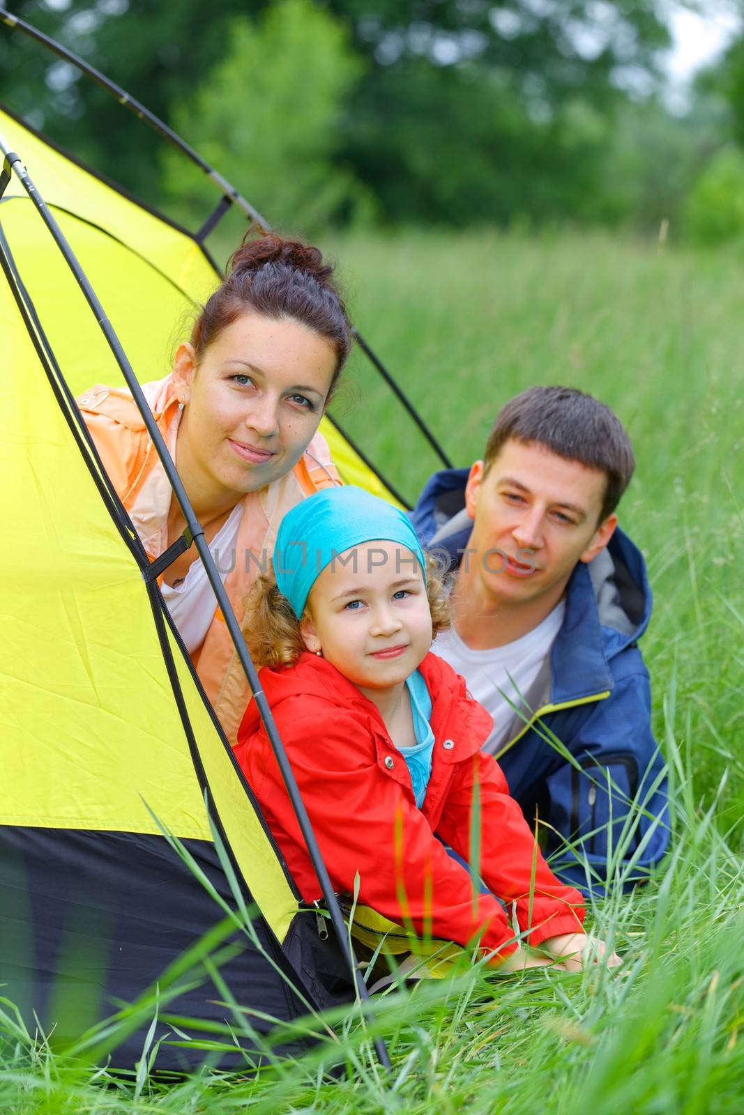 Summer vacation. Family of three in tent in camping on the nature. Vertical view