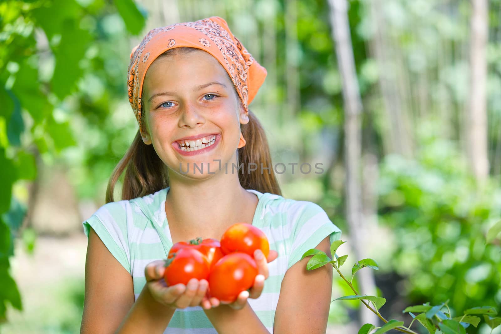 Portrait of beautiful girl holding tomatoes in green garden