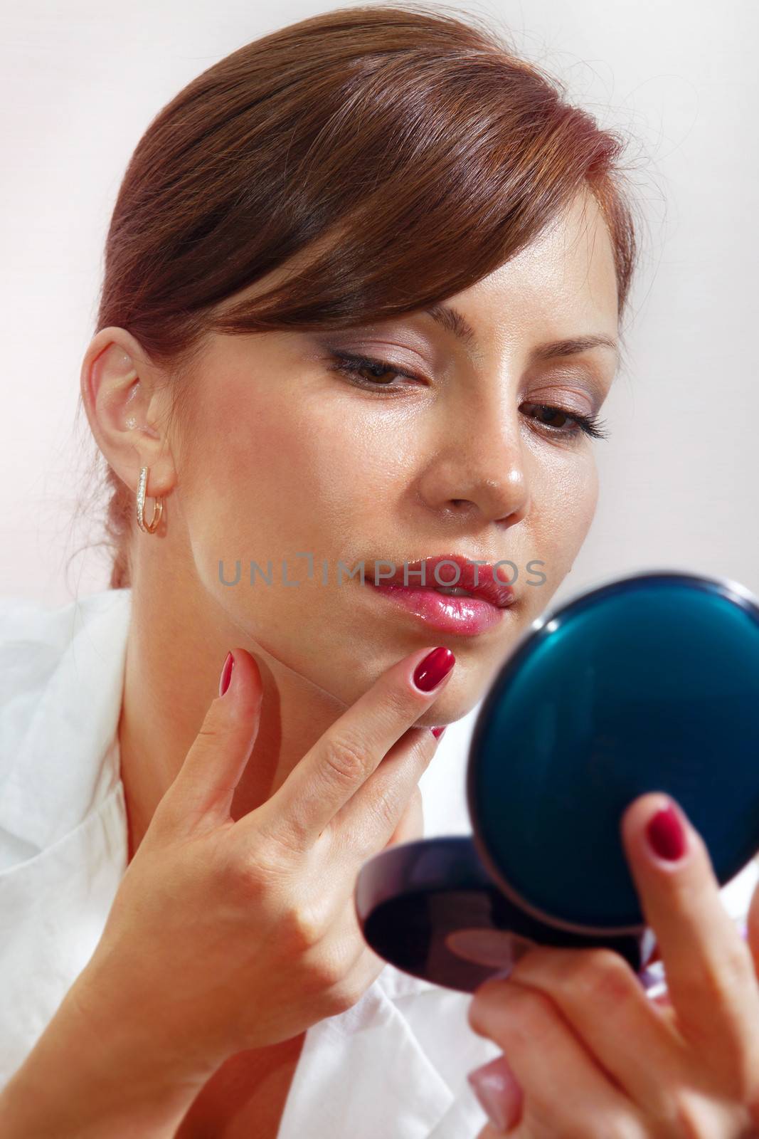 beautiful face smartens up in front of compact mirror