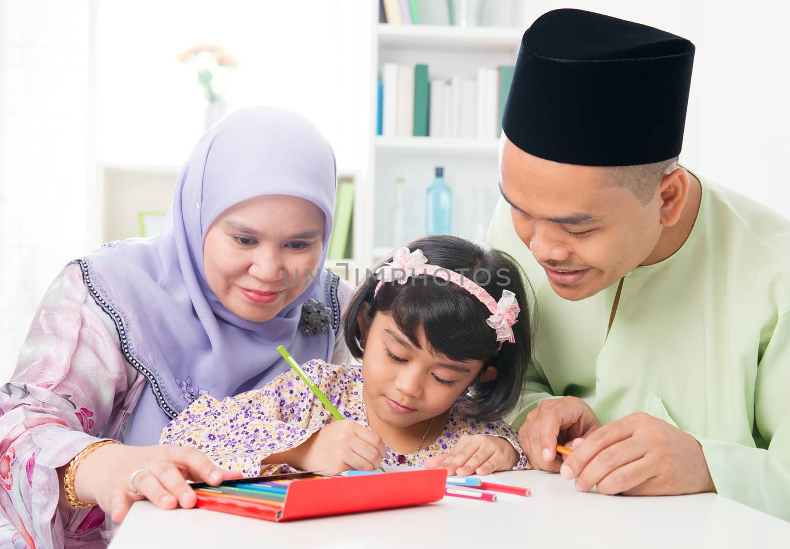 Southeast Asian family drawing and painting picture at home. Muslim family lifestyle. Happy smiling parents and child.