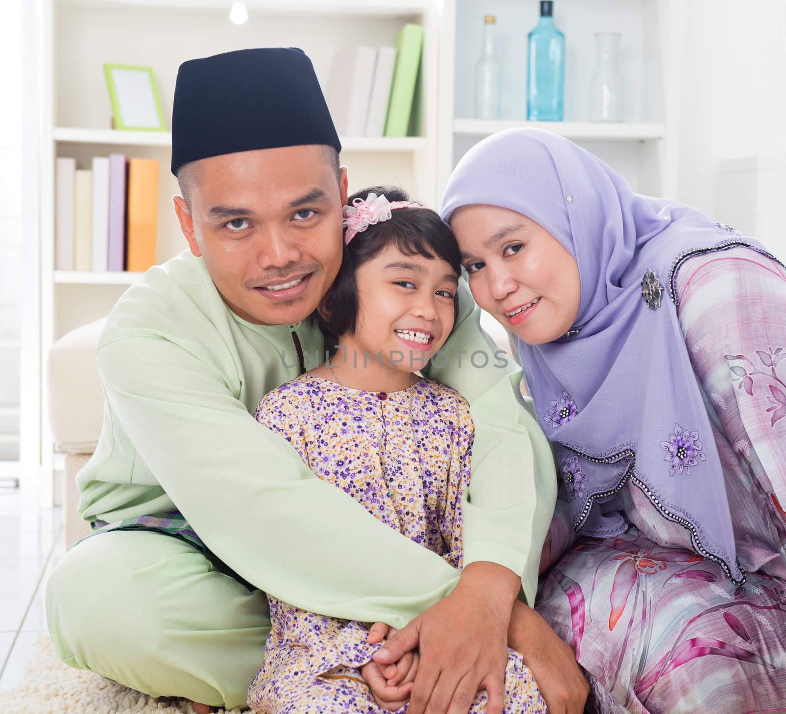 Muslim parents hugging child. Southeast Asian Malay family lifestyle. Happy smiling father mother and daughter.