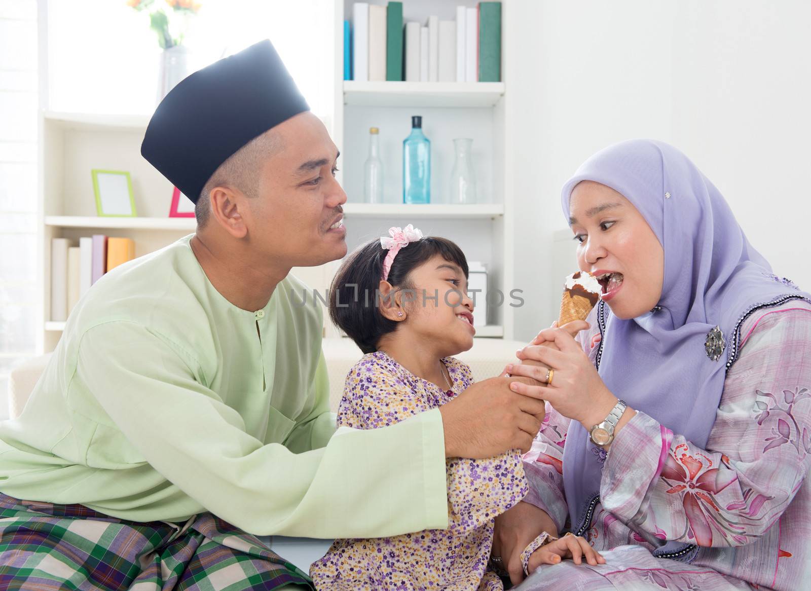 Feeding ice cream. Muslim girl feeding mother an ice cream. Beautiful Southeast Asian family living lifestyle at home.
