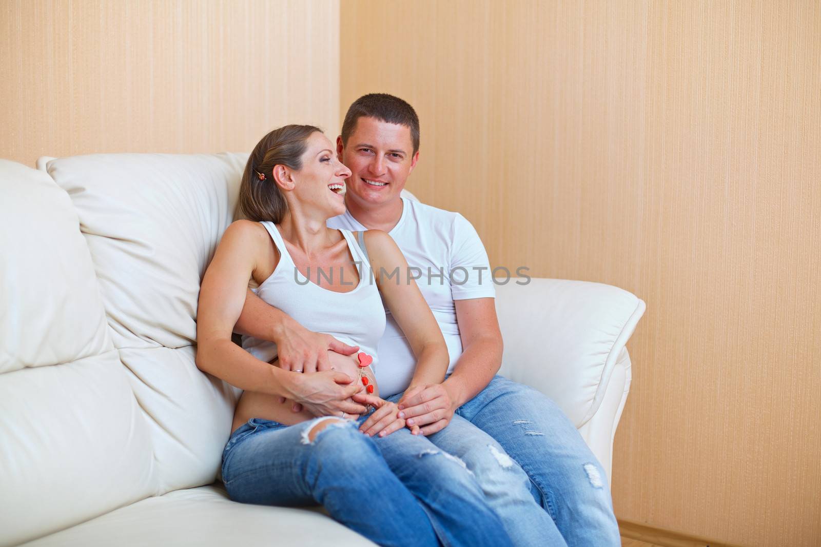 Couple sitting near on the sofa and smiling and pending the kid