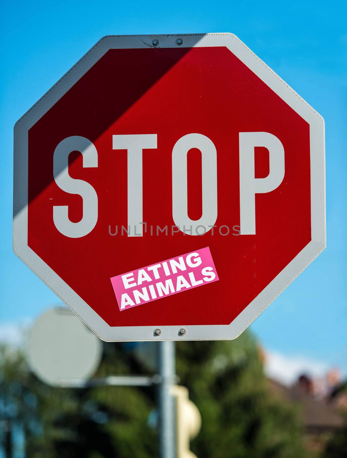 stop roadsign decorated with additional sticker: eating animals
