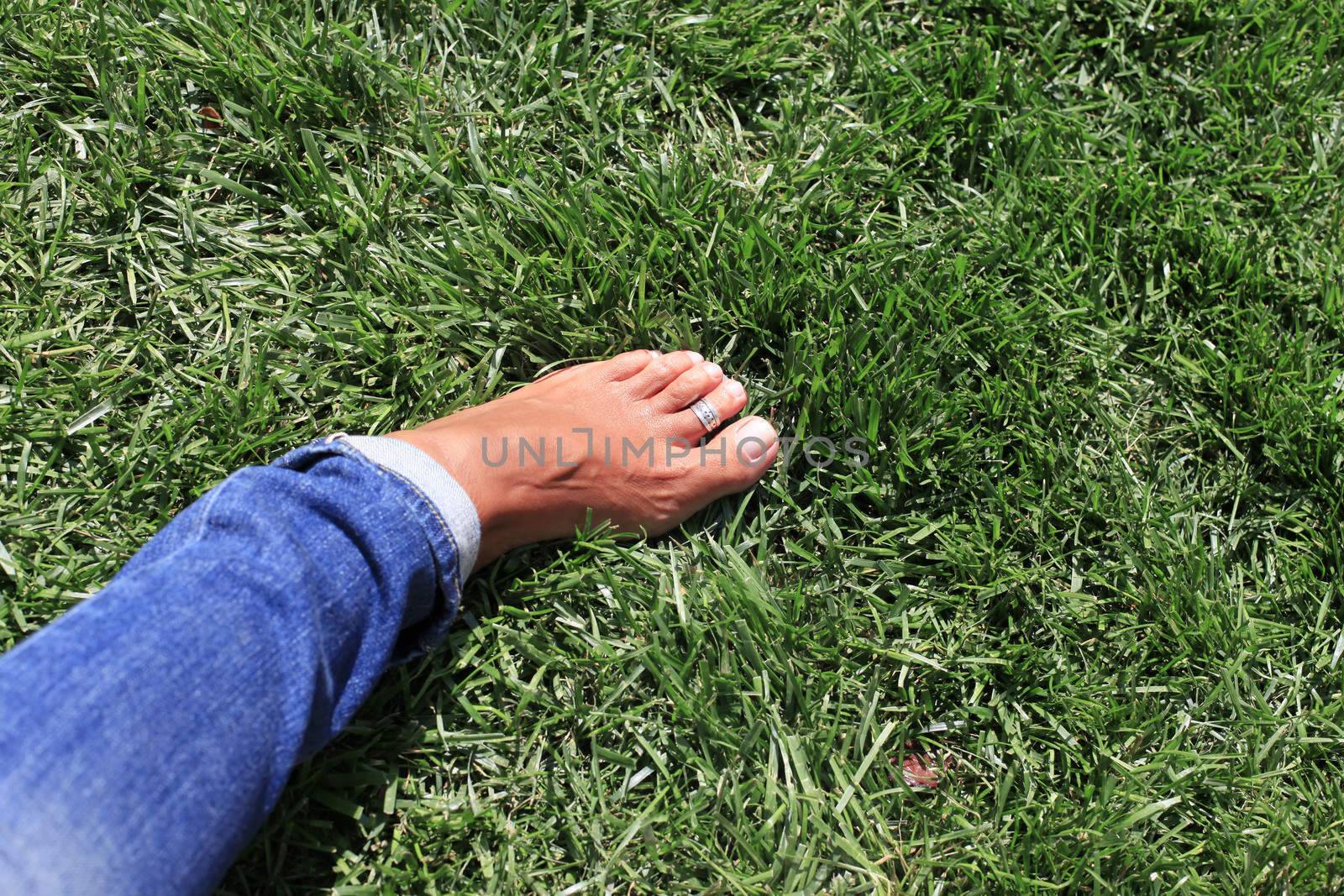 Bare feet in green grass, woman relaxing in nature