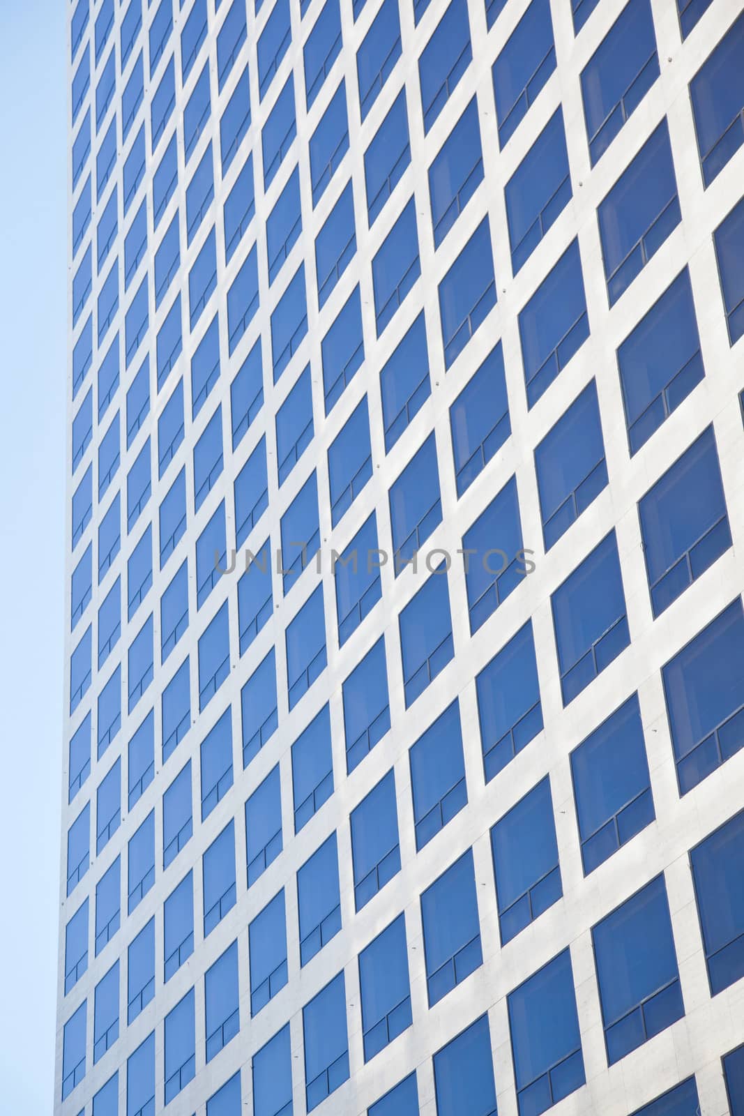 modern office building reflecting blue sky in many square windows
