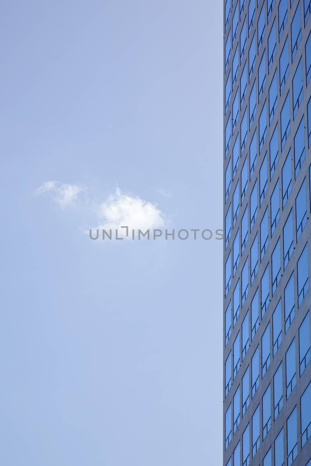 stern facade of office building and one cloud in blue sky