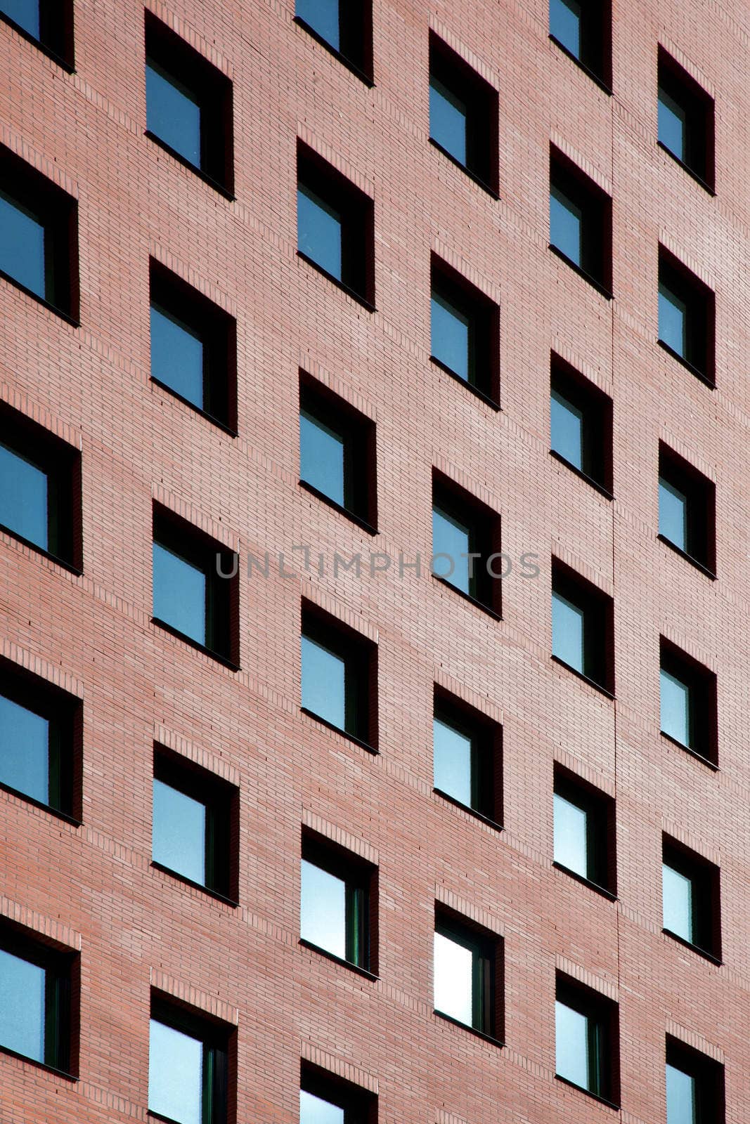 brick facade of office building with many windows reflecting blue sky