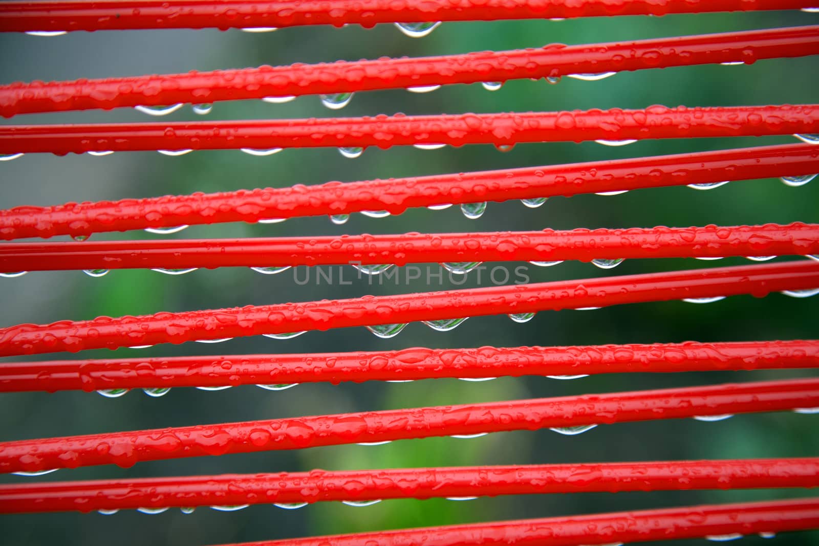 part of red summer chair with raindrops and green background