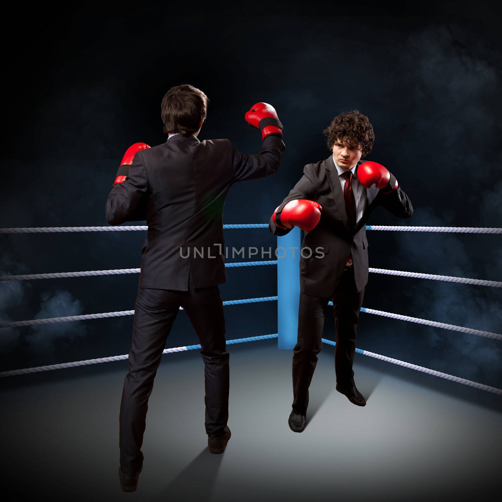 Two young businessman boxing againts dark background . conceptual collage