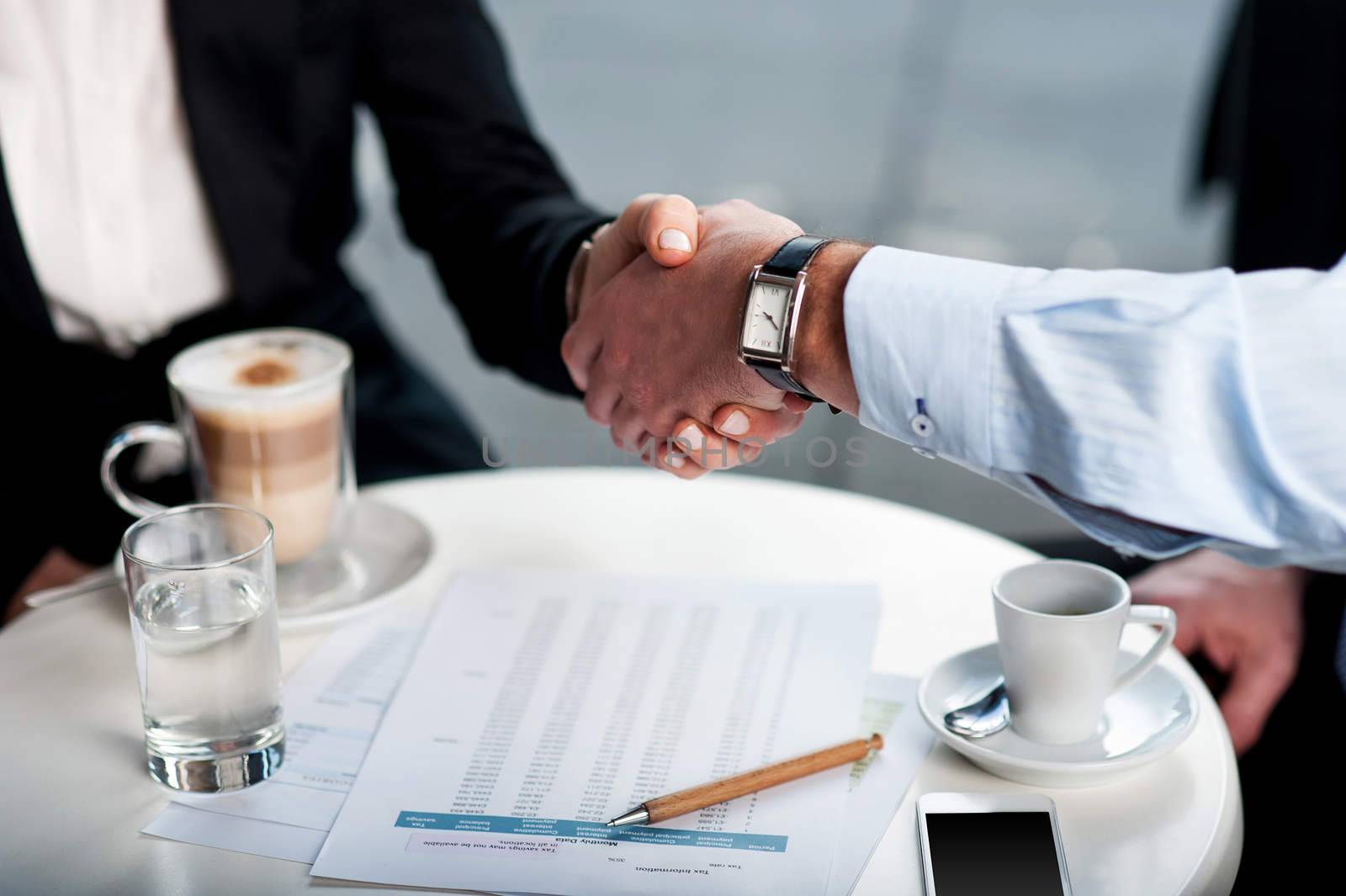 Business handshake over a coffee by stockyimages