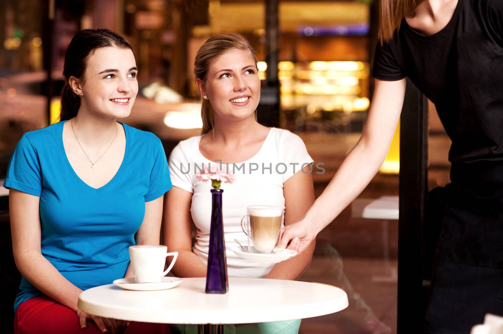 Two beautiful young girls at coffee shop by stockyimages
