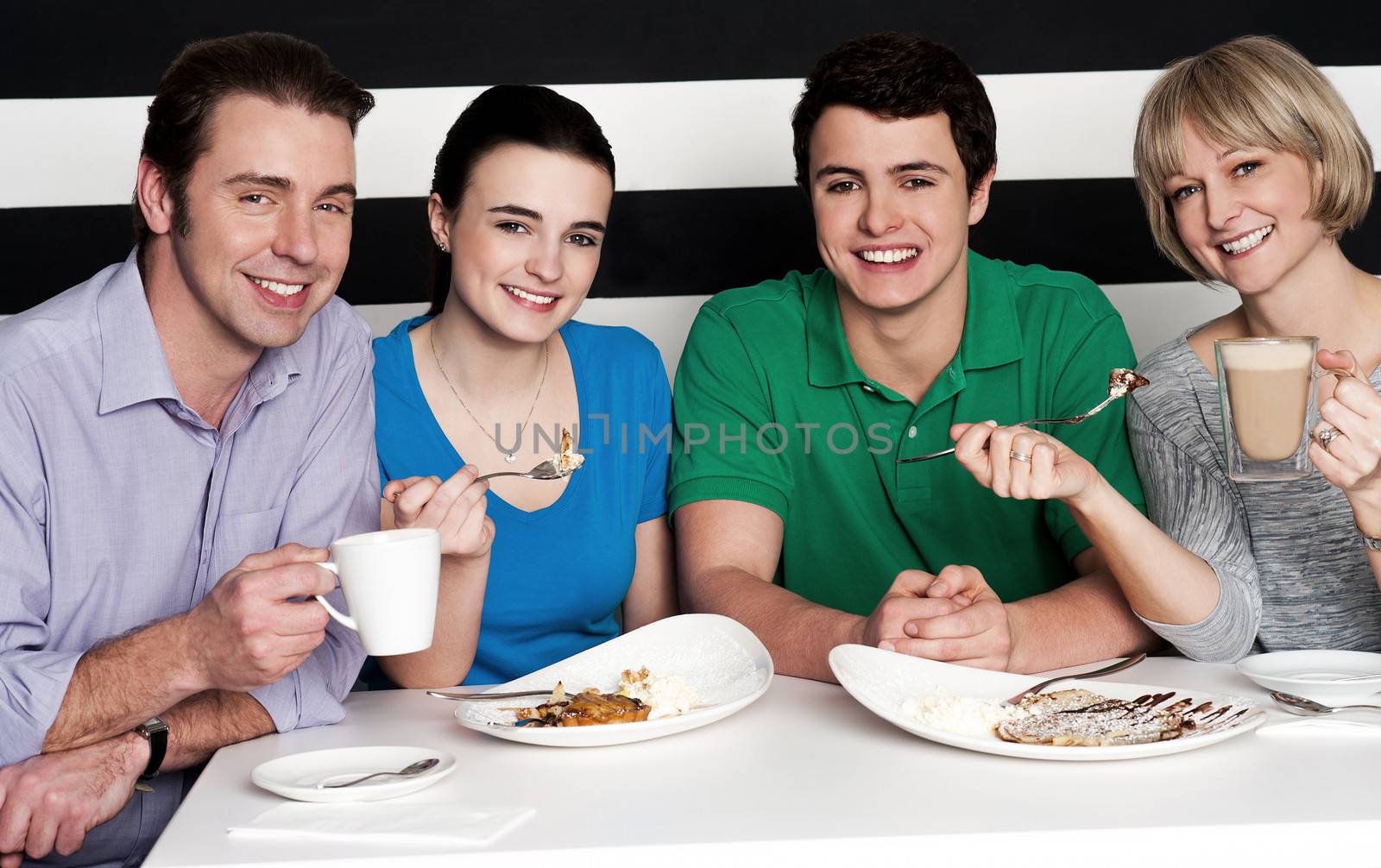 Cheerful family of four relishing nice cuisine breakfast and chocolate shake
