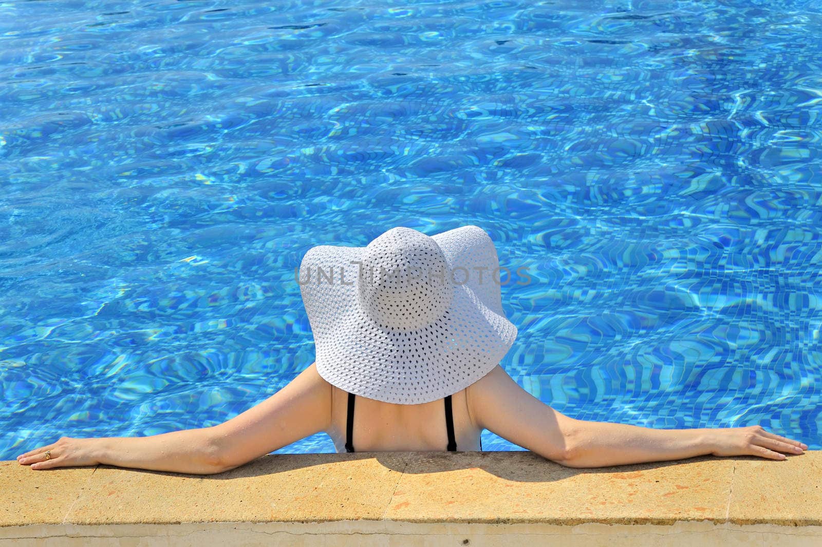 Woman with white hat relaxing at the edge pool