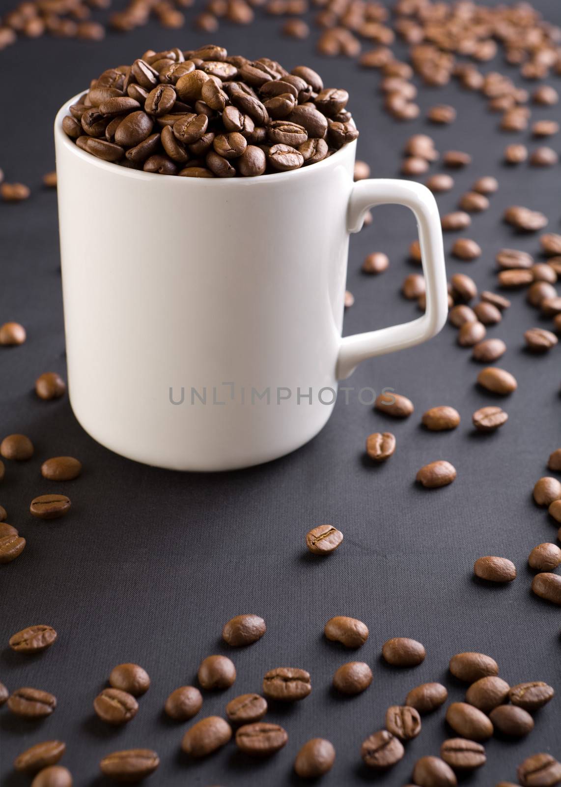 white coffee mug with coffee grains on a black background with coffee grains