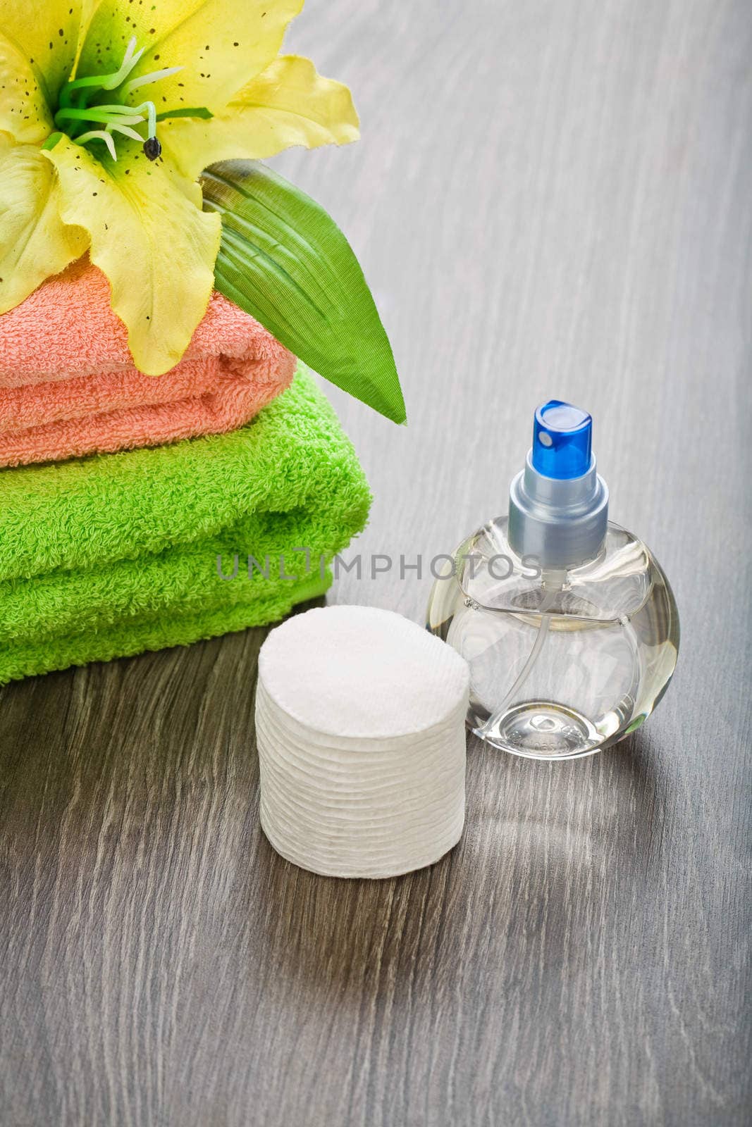 bottle towels flower and cotton pads on wooden background