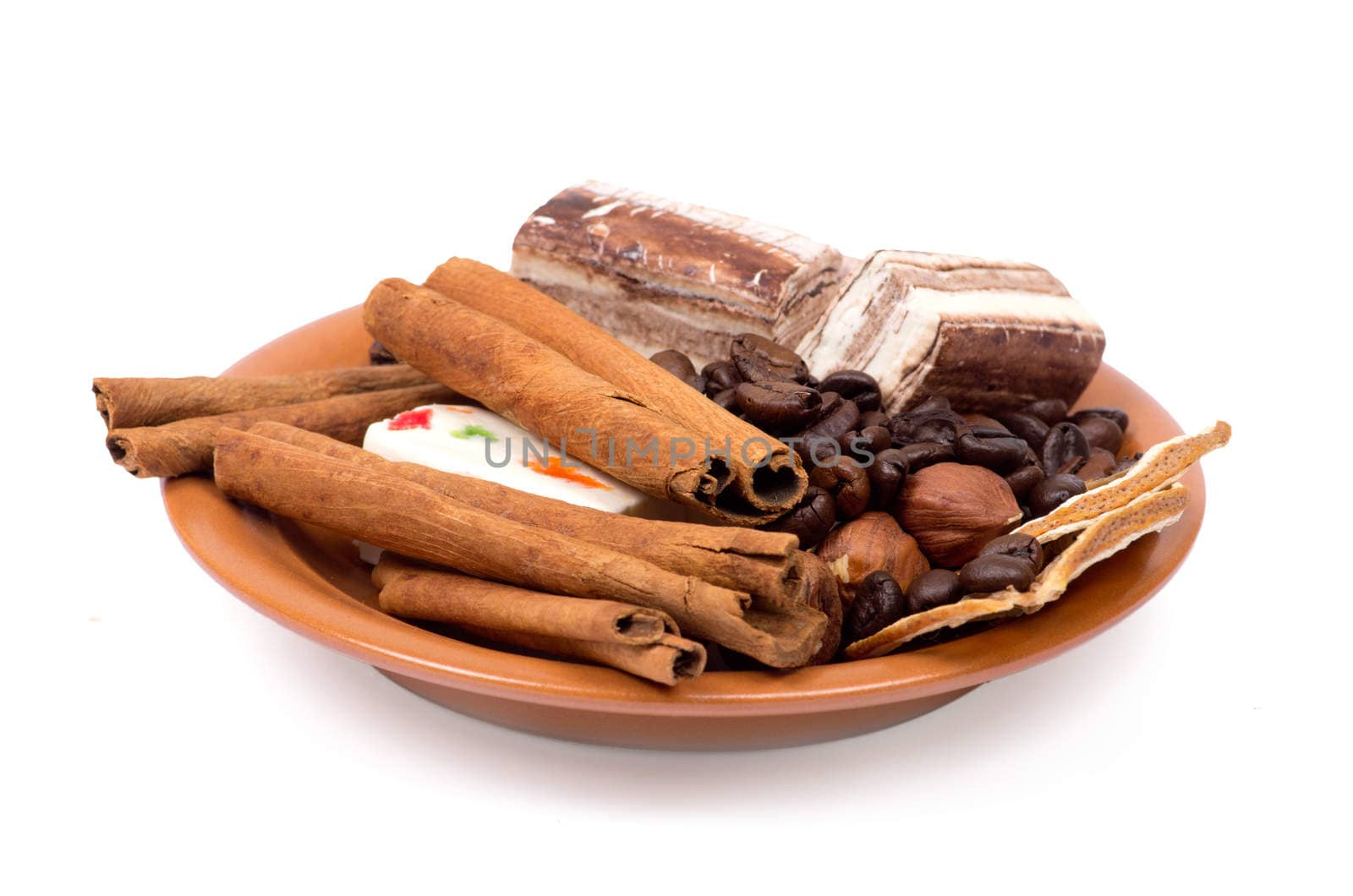 Sweets, cinnamon, nuts and coffee beans on a saucer isolated on white