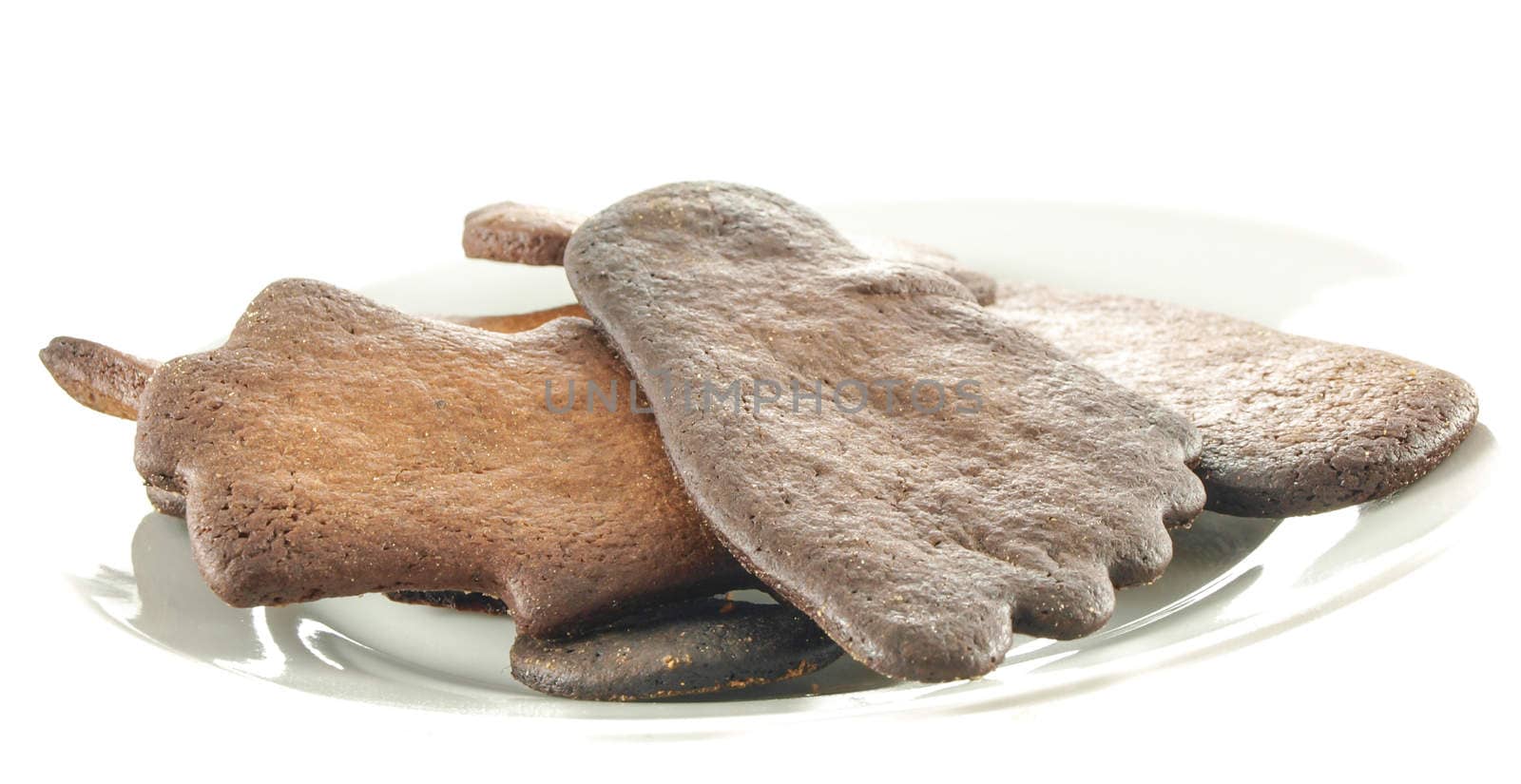 Burned gingerbread cookies on white plate towards white background