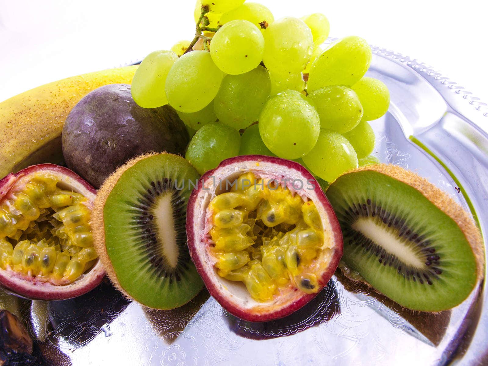 Assorted fruits, isolated on a silver plate, towards white background