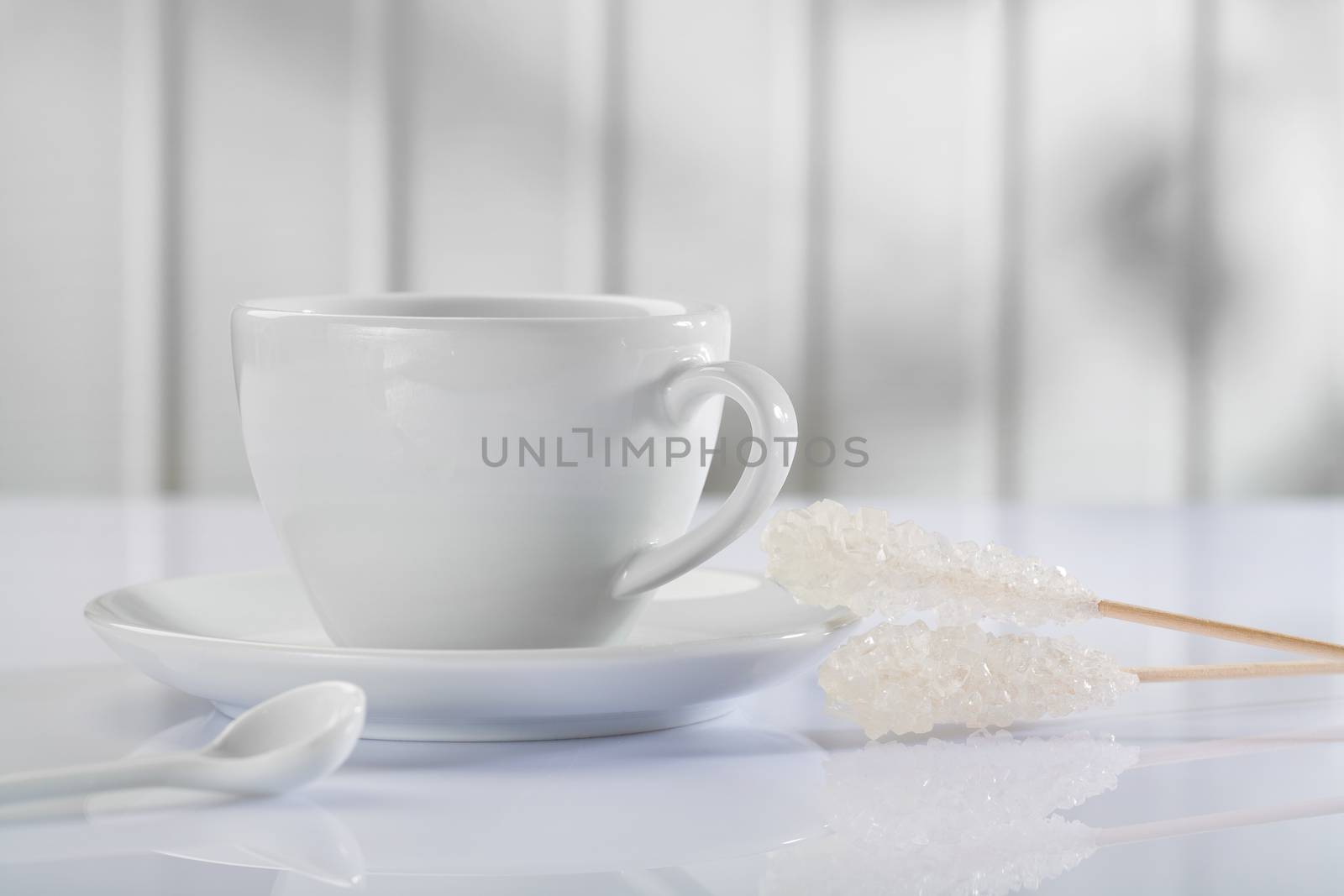 a coffee cup with spoon and sugar stick on white table 