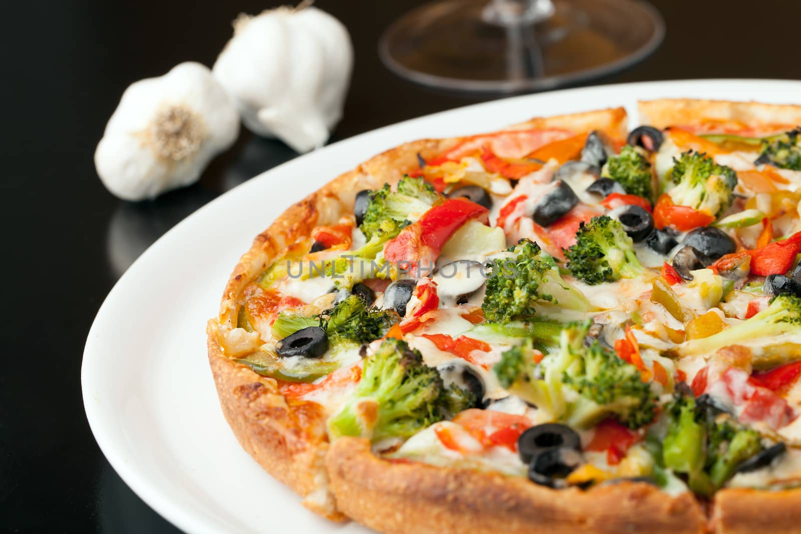 A fresh medium size specialty pizza with extra toppings hot and fresh out of the oven. Shallow depth of field.