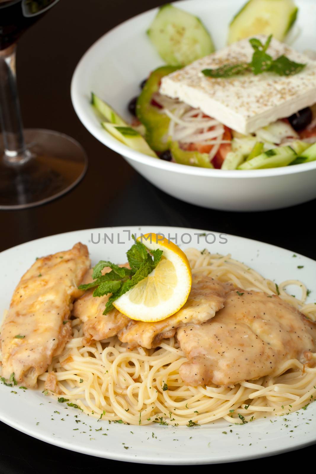 Chicken francaise or francese plated with pasta with salad in the background.