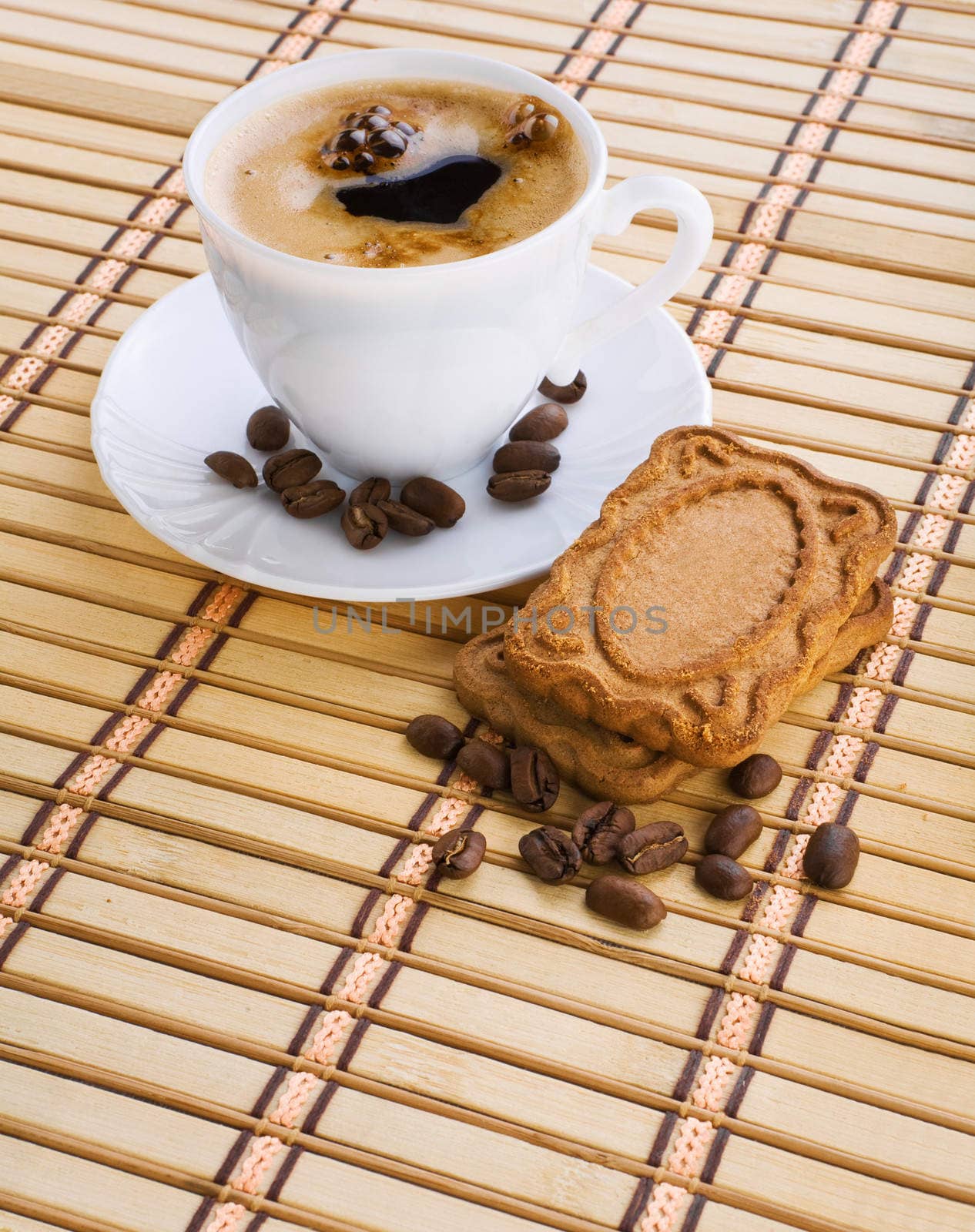 cup of capuchino with coffee beans and cookie on a mat