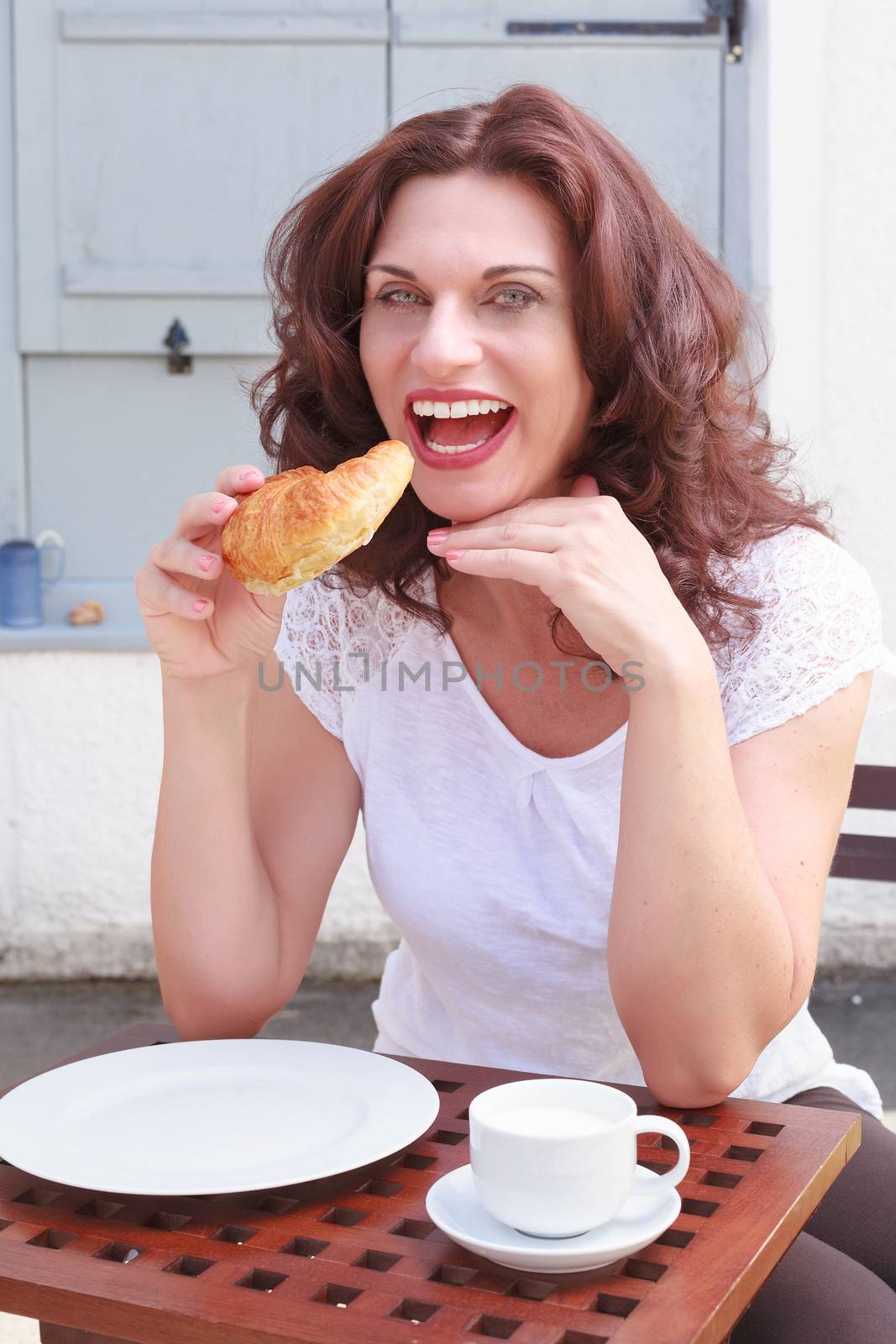 Attractive businesswoman eating a croissant at