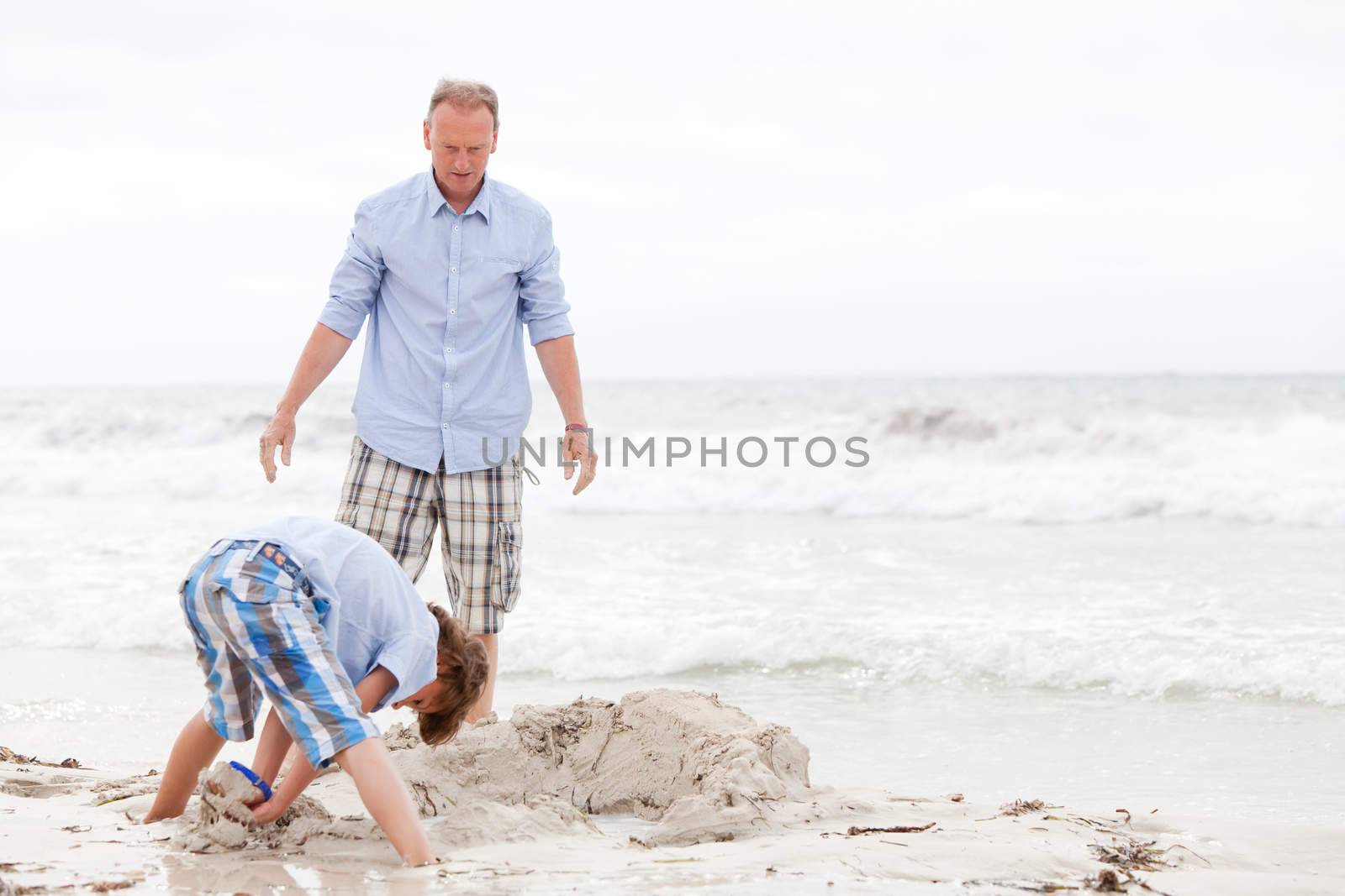 father and sons on the beach playing in the sand holiday family 