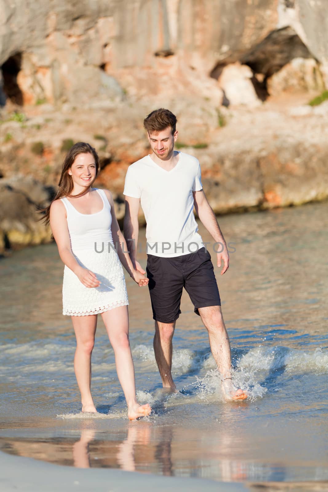 young happy couple walking on beach sunset holiday vacation