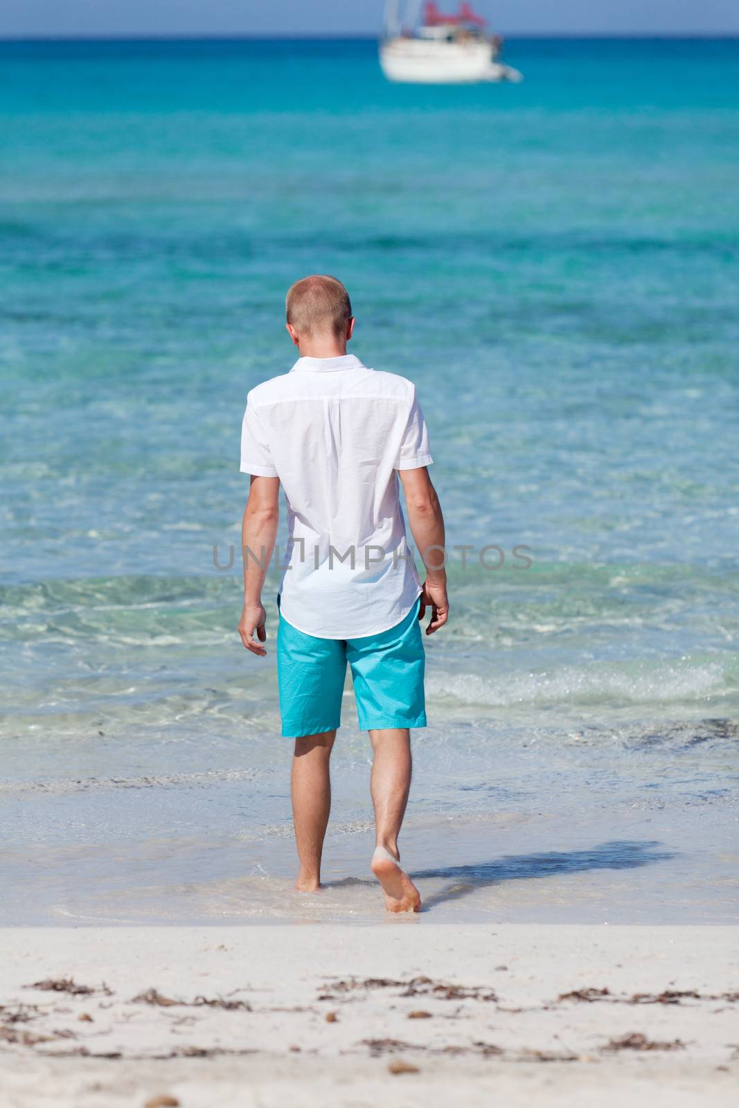 young man walking on the beach in summer holiday vacation