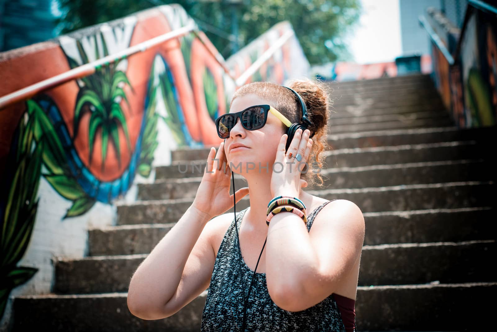 beautiful stylish modern young woman listening to music in the city