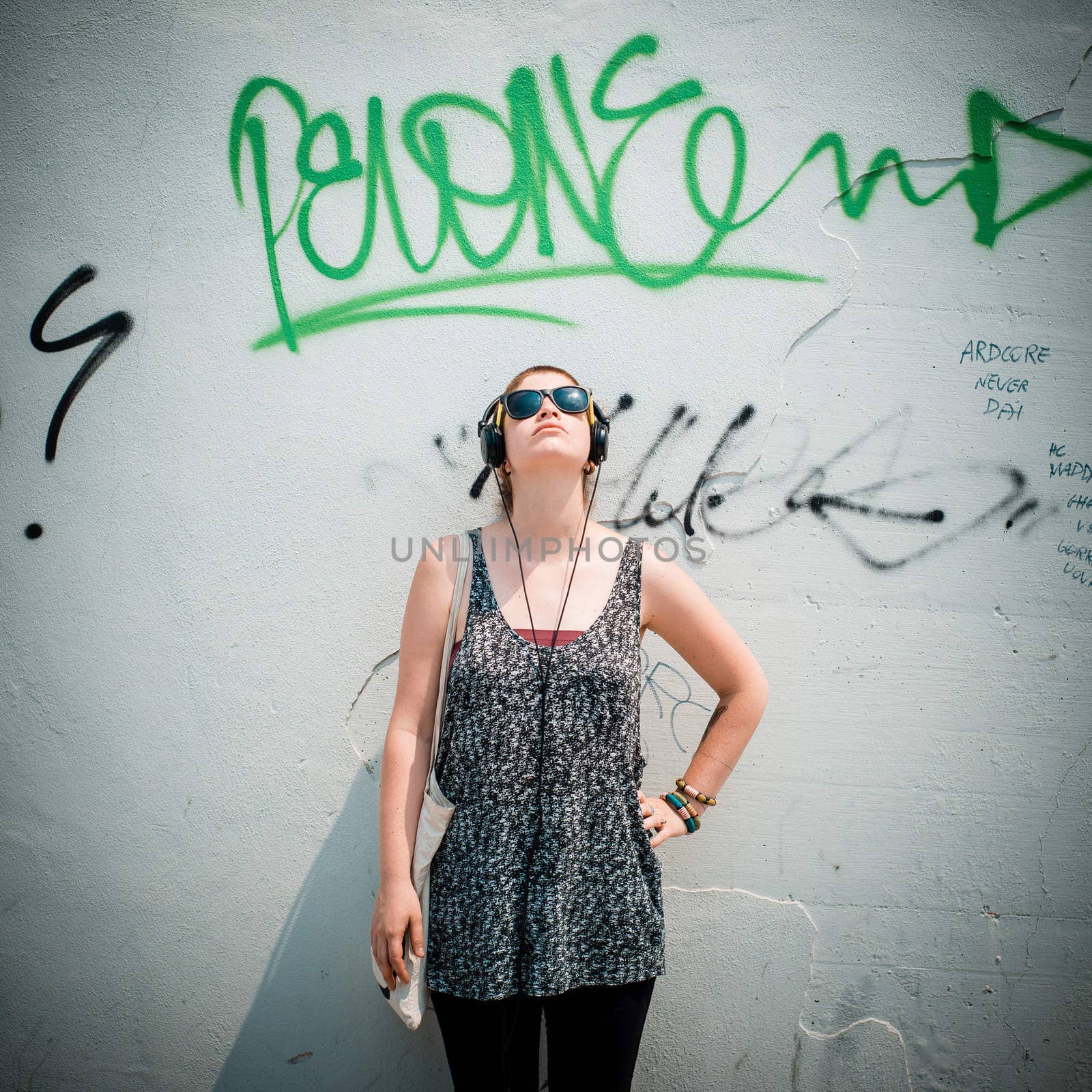 beautiful stylish modern young woman listening to music in the city