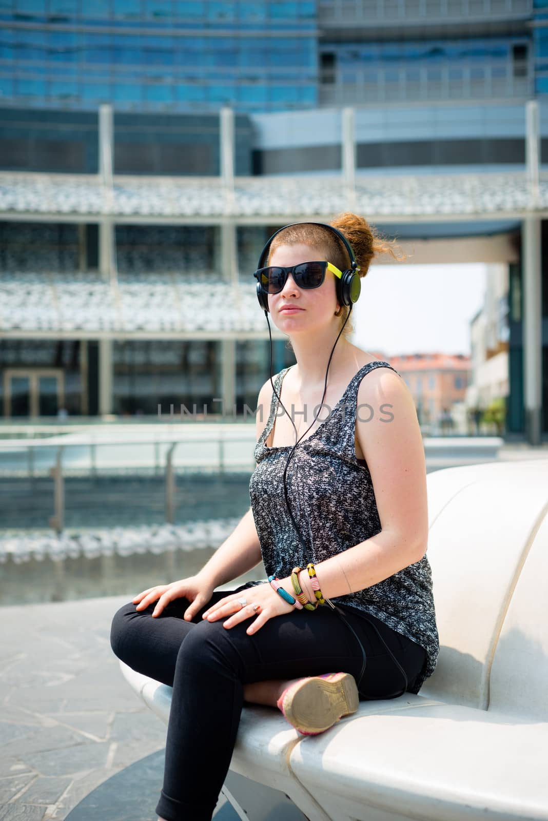 beautiful stylish modern young woman listening to music in the city